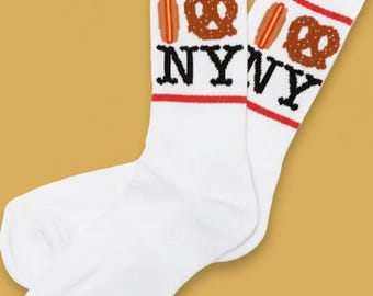 May include: White socks with red stripes at the top, featuring a hot dog and pretzel graphic above the letters "NY". The socks are a fun and casual accessory.