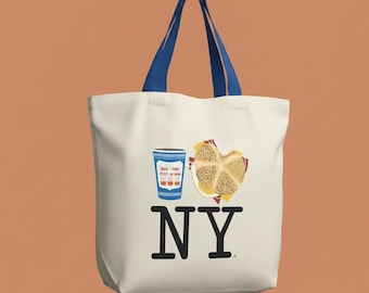 May include: Off-white tote bag with blue handles featuring a cartoon illustration of a coffee cup, a sandwich, and the letters "NY" in black. The coffee cup has a blue and white design, and the sandwich is on a red and white checkered napkin.
