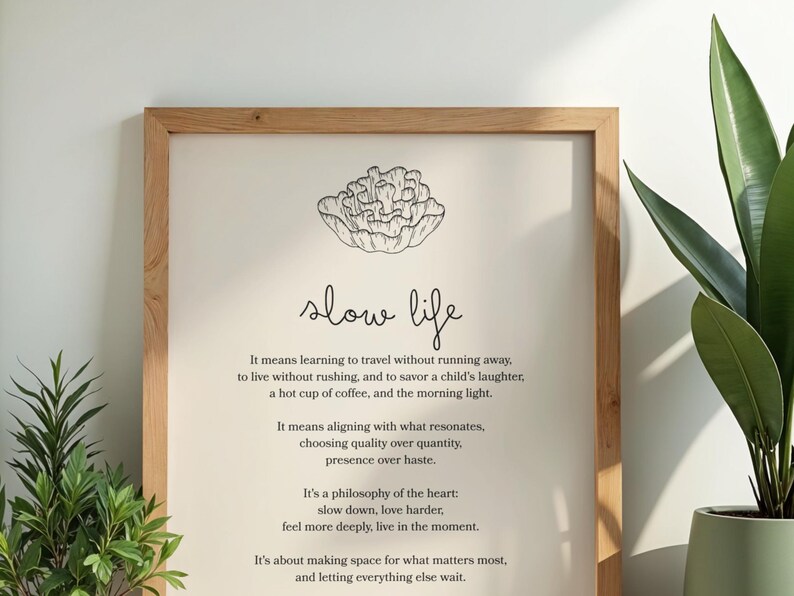 May include: Wooden framed print with the words "slow life" in a handwritten font. The print includes a floral illustration and text about slowing down and appreciating life's simple pleasures. A potted plant is visible on the right.