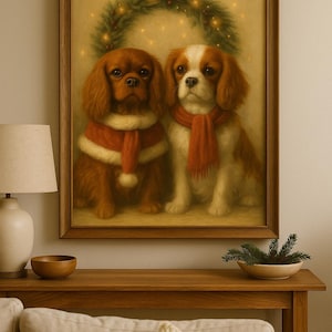 Puede incluir: Pintura enmarcada de dos Cavalier King Charles Spaniels. Un perro es marrón, con una bufanda y abrigo rojos y blancos. El otro es blanco y marrón, con una bufanda roja. Una corona navideña está encima.