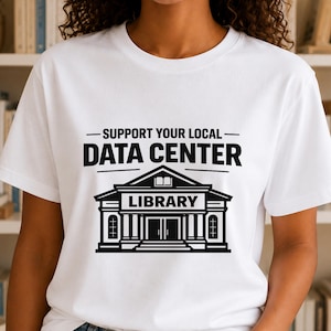 May include: A white short-sleeved t-shirt featuring a black graphic print. The design displays the text SUPPORT YOUR LOCAL DATA CENTER above an illustration of a building with columns and the word LIBRARY printed on the front facade.