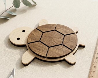 Peut inclure: Un puzzle en bois en forme de tortue avec une tête et des membres de couleur claire et une carapace segmentée brun foncé. L'article est présenté comme un téléchargement numérique avec les formats SVG, DXF et AI sur une petite carte.