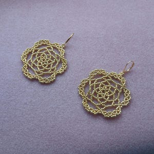 May include: A white ceramic mug with a black handle and the text "But First, Coffee" in a bold, black font. The mug is set against a blurred background, suggesting a cozy setting.