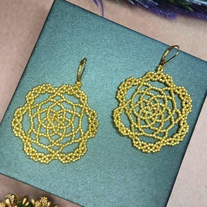 May include: A white ceramic mug with a black handle and the text "But First, Coffee" in a bold, black font. The mug is set against a blurred background, suggesting a cozy setting.