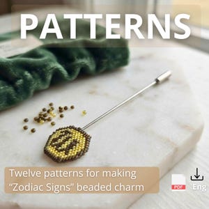 Puede incluir: Un alfiler de solapa de metal plateado con un pequeño dije circular de cuentas con un diseño zodiacal en amarillo y marrón. Se acompaña de cuentas sueltas y un documento PDF titulado Twelve patterns for making Zodiac Signs beaded charm.