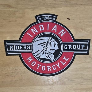 Peut inclure: Écusson brodé avec les mots "Indian Motorcycle" dans un design circulaire, avec un profil amérindien. L'écusson comprend le texte "Riders Group" et "Est. 1901 USA" dans un schéma de couleurs noir et rouge.