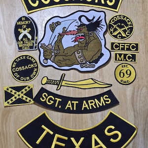 May include: A collection of black and yellow embroidered patches with various designs and text. The patches include the word "COSSACKS", a cartoon figure, a sword, and the text "TEXAS".