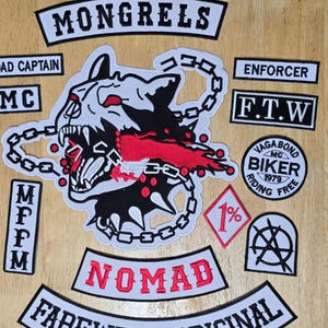Op de afbeelding: Een verzameling geborduurde patches met diverse ontwerpen en tekst. De patches bevatten de woorden "MONGRELS", "NOMAD", "FAREWELL ORIGINAL", "ENFORCER" en "F.T.W". Een centrale patch toont een hondenhoofd met een ketting.