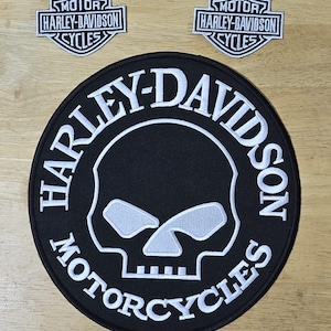 May include: Black and white Harley-Davidson patches. The large patch features a skull design with the words "HARLEY-DAVIDSON MOTORCYCLES." Two smaller patches display the Harley-Davidson logo with the text "MOTOR HARLEY-DAVIDSON CYCLES."