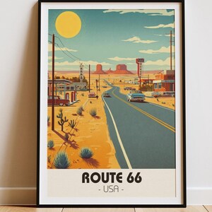 Op de afbeelding: Een ingelijste kunstdruk met een gestileerde illustratie van Route 66 in de VS. Het kunstwerk toont een woestijnlandschap met een weg, oldtimers en een grote gele zon. De tekst "ROUTE 66 - USA" staat onderaan.