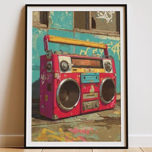 Puede incluir: Impresión enmarcada de una ilustración de boombox vintage al estilo grafiti. La boombox es principalmente roja con detalles amarillos, azules y plateados. Se encuentra sobre una pared turquesa con arte de grafiti.