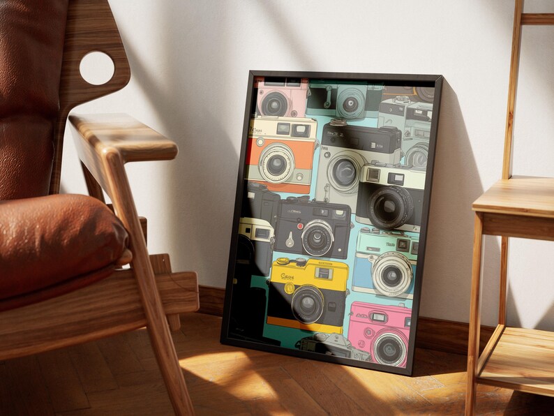 Pu&ograve; includere: Una stampa artistica incorniciata con un collage di fotocamere vintage in vari colori, tra cui rosa, arancione, giallo e nero. Le fotocamere sono disposte su uno sfondo azzurro. La stampa &egrave; esposta accanto a una sedia di legno.