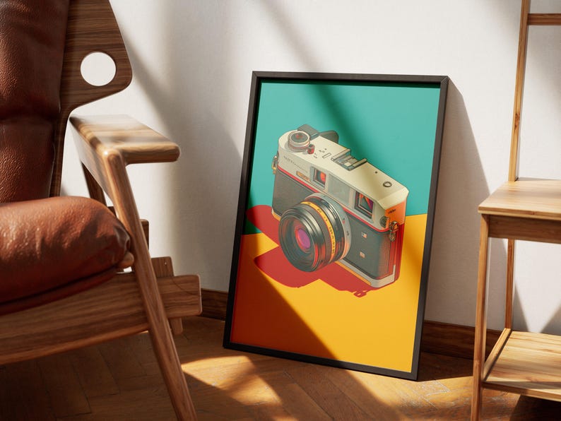 May include: A framed art print featuring a vintage camera illustration. The camera is depicted in a retro style with a black, silver, and orange color scheme, set against a teal, yellow, and red background. The artwork is displayed in a black frame.