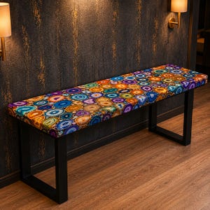 May include: A rectangular bench with a colorful agate stone pattern top and a black metal frame. The agate design features a mosaic of circular patterns in shades of blue, orange, yellow, and purple. The bench is approximately 60 inches long.