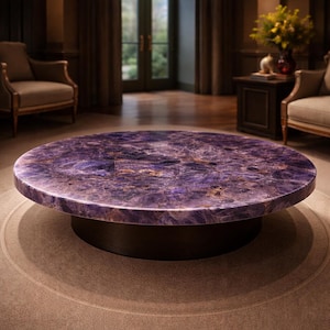Puede incluir: Una mesa de centro redonda con una superficie de amatista pulida. La mesa tiene una base marrón oscuro y se apoya sobre una alfombra marrón claro. La superficie de amatista tiene un color púrpura intenso con vetas doradas y blancas.