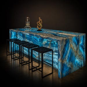 May include: A backlit blue onyx bar with a textured surface and a gold-colored sculpture. Four black stools with square seats are in front of the bar. A glass decanter sits on the bar. The text "BLUE ONYX BAR" is visible.