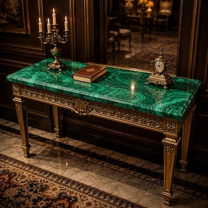 Puede incluir: Una mesa consola rectangular con una superficie de malaquita verde pulida y patas doradas ornamentadas. Sobre la mesa hay un candelabro dorado con cuatro velas encendidas, un libro marrón cerrado y un pequeño reloj dorado con esfera blanca.