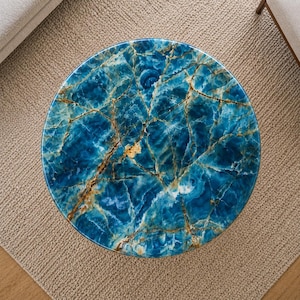 May include: A round coffee table with a striking blue marble top. The marble features intricate veining in shades of blue, white, and gold. The table's design is modern and elegant, perfect for a living room or lounge area.