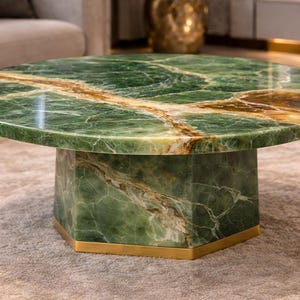 May include: A circular coffee table with a green marble top and a hexagonal base. The marble features brown and gold veining. The base is green marble with a gold-coloured metal trim.