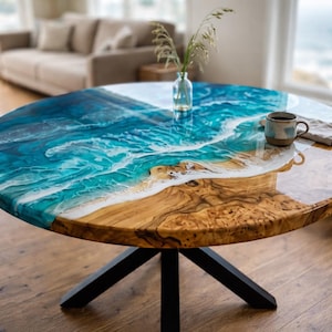Pode incluir: Mesa de centro redonda com um design único com tema oceânico. A mesa apresenta uma base de madeira e um tampo de resina que retrata uma cena de praia com ondas azuis e brancas. É suportada por pernas de metal preto. Aproximadamente 100 cm de diâmetro.
