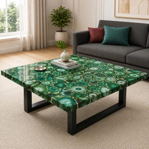 Puede incluir: Una mesa de centro cuadrada con un tablero compuesto por numerosas rodajas de ágata verde con bordes dorados, sostenida por una estructura de metal negro. La superficie muestra un mosaico de patrones verdes circulares e irregulares.