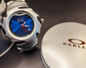 Reloj Oakley estilo Blade: reloj de pulsera futurista con esfera azul estilo Y2K y detalles plateados.