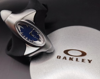 Reloj Oakley estilo torpedo: esfera azul, diseño minimalista futurista estilo Y2K, correa negra.