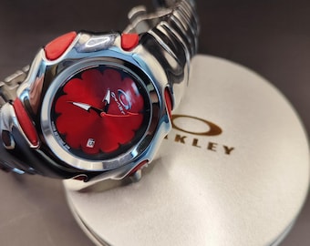 Reloj Oakley Blade Style: un reloj de pulsera plateado con un diseño futurista Y2K y esfera de flores rojas.