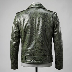 Peut inclure: Veste en cuir vert &agrave; motif peau de serpent, de style motard classique. Elle pr&eacute;sente un col crant&eacute;, des &eacute;paulettes et une ceinture &agrave; la taille. La veste est pr&eacute;sent&eacute;e sur un mannequin, mettant en valeur sa coupe ajust&eacute;e et ses d&eacute;tails.