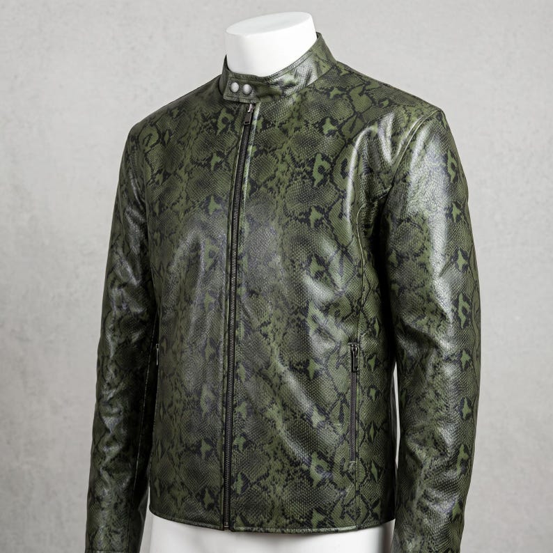 Peut inclure: Veste &agrave; motif peau de serpent vert et noir, avec un col montant et une fermeture &eacute;clair sur le devant. La veste a un design &eacute;l&eacute;gant et moderne avec un &eacute;clat subtil. La veste est pr&eacute;sent&eacute;e sur un buste blanc.