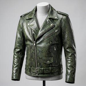 Peut inclure: Veste de motard en cuir vert &agrave; motif peau de serpent. Elle pr&eacute;sente un col crant&eacute;, une fermeture &eacute;clair asym&eacute;trique, plusieurs poches zipp&eacute;es et une taille ceintur&eacute;e. La veste est pr&eacute;sent&eacute;e sur un mannequin.