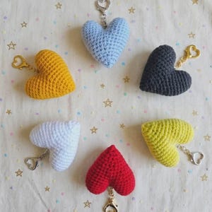 Peut inclure: Six porte-clés en crochet en forme de cœur, déclinés en bleu clair, gris foncé, jaune moutarde, blanc, rouge vif et vert citron. Chaque cœur en peluche est doté d'un fermoir mousqueton en métal doré, avec un motif de mailles texturé.