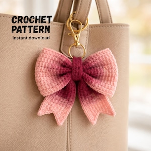 May include: A handmade crochet bow keychain in shades of pink and burgundy, attached to a beige handbag with a gold-colored clasp. The text "CROCHET PATTERN instant download" is visible.