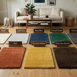 May include: A range of rectangular rugs in colours such as beige, light grey, navy blue, emerald green, charcoal, burgundy, rust, mustard yellow, chocolate brown, and blush pink. The rugs are displayed on a wooden floor.