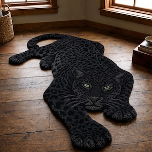 May include: A black leopard-shaped rug featuring a dark charcoal and black spotted pattern with two piercing green eyes. The rug is designed in the silhouette of a crouching big cat with a long tail, detailed paws, and a textured, tufted surface.