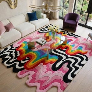 May include: A large, rectangular area rug featuring a vibrant, multi-colored design with wavy, organic lines. The pattern includes a central rainbow gradient of red, orange, yellow, green, and blue, surrounded by bold black and white wavy stripes.