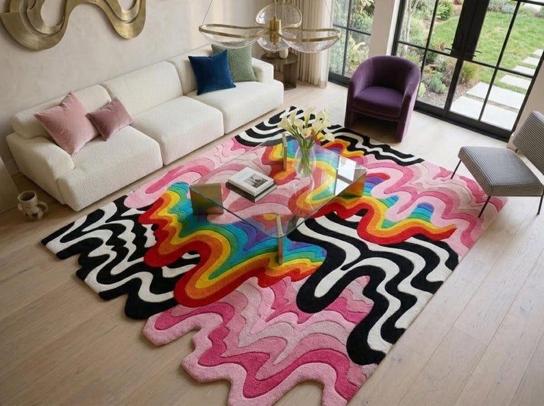 May include: A large, rectangular area rug featuring a vibrant, multi-colored design with wavy, organic lines. The pattern includes a central rainbow gradient of red, orange, yellow, green, and blue, surrounded by bold black and white wavy stripes.