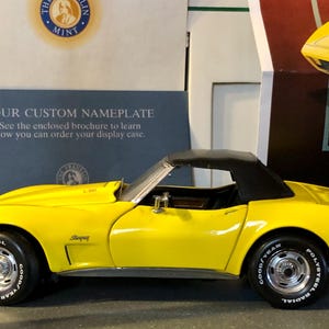 Puede incluir: Un coche modelo amarillo con capota negra descapotable. El coche tiene neumáticos negros con letras blancas que dicen "POLYSTEEL RADIAL" y "GOOD YEAR". El texto "YOUR CUSTOM NAMEPLATE" es visible en el fondo.