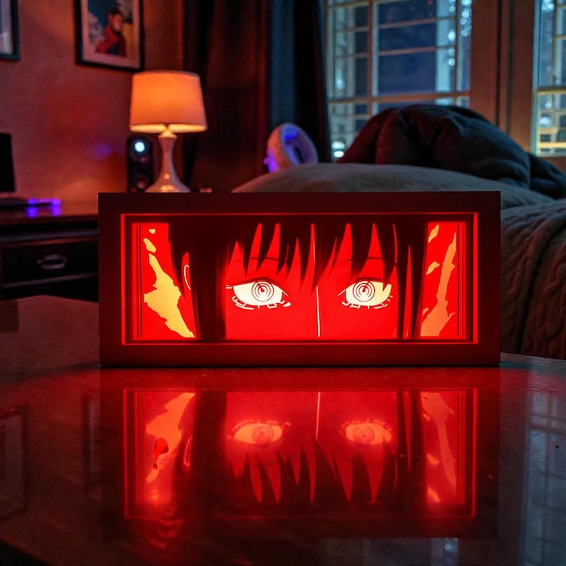 Pu&ograve; includere: Un'opera d'arte rettangolare illuminata in stile anime. L'opera presenta un paio di grandi occhi stilizzati con iridi bianche e pupille nere, su sfondo rosso. Il pezzo &egrave; in una cornice di legno, che proietta un bagliore rosso.