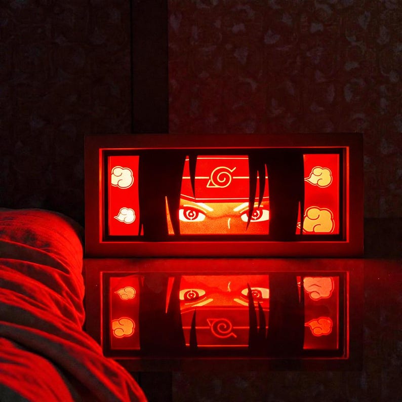 Pu&ograve; includere: Una luce notturna rettangolare rossa a tema anime, con gli occhi e la fascia di un personaggio. Il design include nuvole stilizzate e un simbolo, con un riflesso a specchio. La cornice &egrave; marrone caldo.
