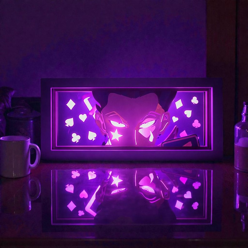 Pu&ograve; includere: Un'opera d'arte incorniciata e illuminata con un personaggio anime illuminato di viola con un design a stella e lacrima. Lo sfondo include simboli di carte da gioco. L'opera d'arte si riflette su una superficie scura.
