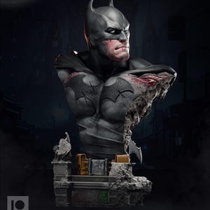 Può includere: Busto dettagliato di Batman in grigio e nero. La statua presenta un petto danneggiato che rivela la struttura interna. Il busto è posto su una base di pietra con dettagli dorati e un'emblema verde.