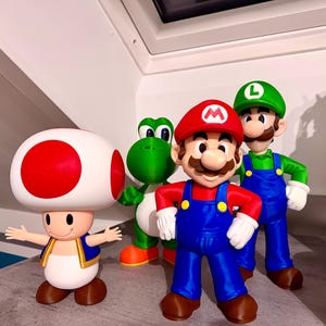 Könnte beinhalten: Eine Sammlung farbenfroher Figuren mit Charakteren aus der Super Mario-Reihe. Die Figuren umfassen Mario, Luigi, Yoshi und Toad. Mario trägt einen roten Hut und blaue Latzhosen. Luigi trägt einen grünen Hut und blaue Latzhosen. Yoshi ist grün und Toad hat einen großen Pilzhut.