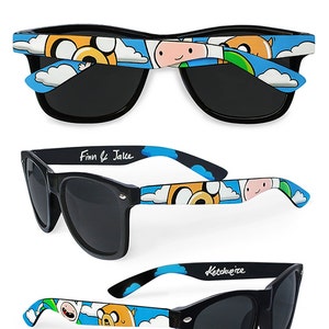 Picture of black sunglasses, hand-painted with an Adventure Time inspired design, including Finn the human and Jake the dog on a blue background with white clouds, in white, blue and yellow colors.