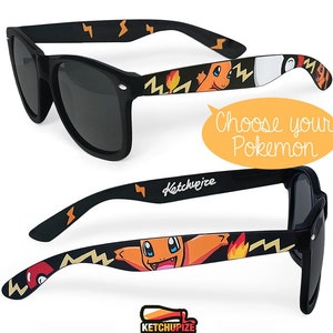 Picture of black sunglasses, hand-painted with a Pokémon design, including orange Charmander and red and white Pokeballs on a black background, in orange, yellow and red colors.