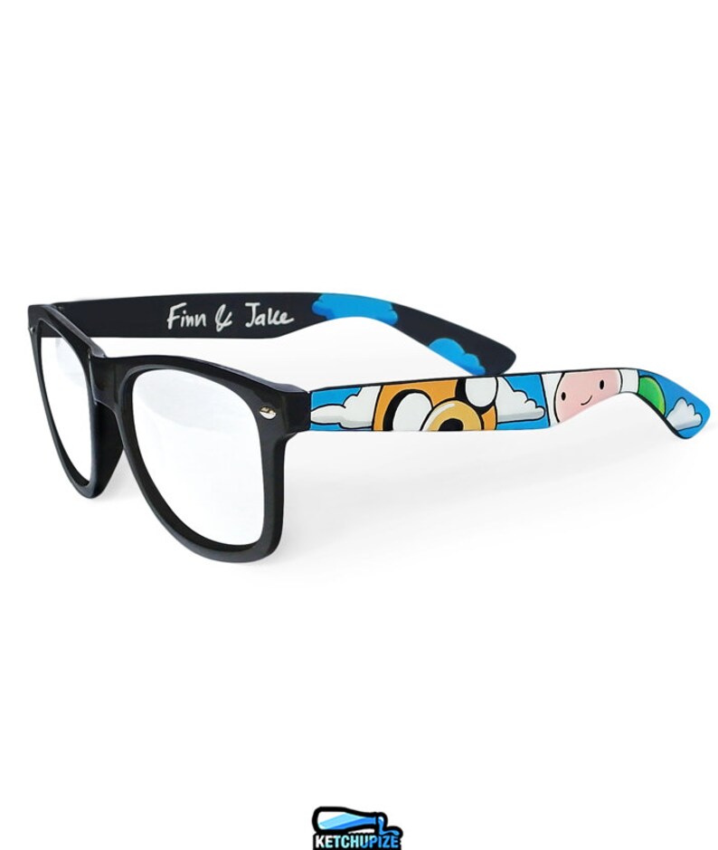 Picture of black clear lens glasses, hand-painted with an Adventure Time inspired design, including Finn the human and Jake the dog on a blue background with white clouds, in white, blue and yellow colors.