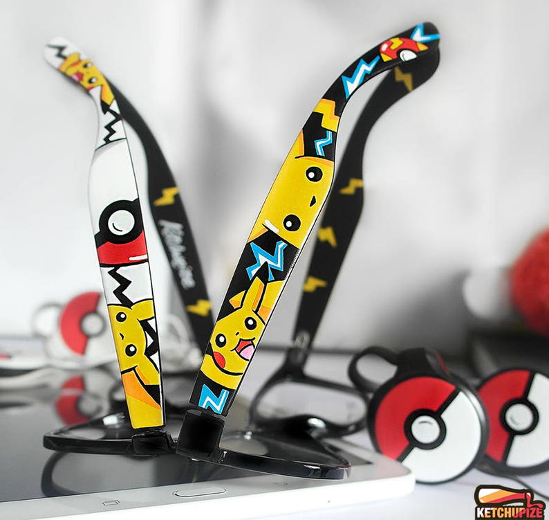 Picture of two black clear lens glasses, hand-painted with a Pokemon design, including yellow Pikachu, blue and white bolts and red and white Pokeballs, in white, black, yellow, red and blue colors.