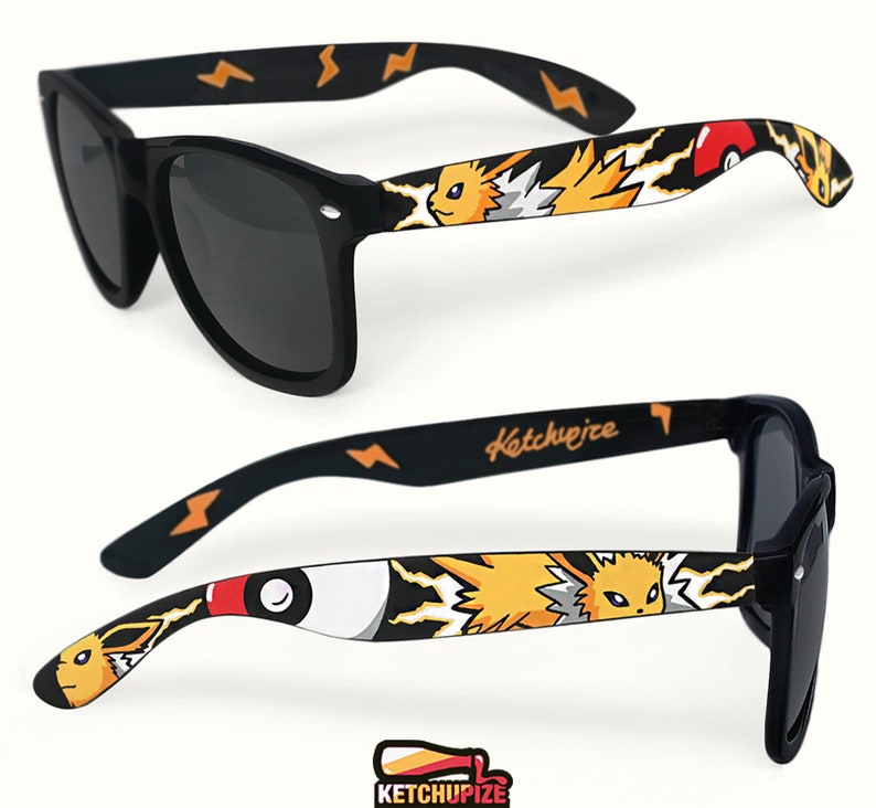 Picture of black sunglasses, hand-painted with a Pokémon design, including Jolteon and red and white Pokeballs on a black background, in orange, yellow and red colors.