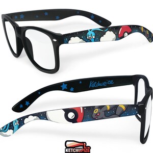 Picture of black prescription glasses, hand-painted with a Pokémon design, including Umbreon and Altaria and red and white Pokeballs on a black starry sky background, in white, blue, grey, black and red colors.