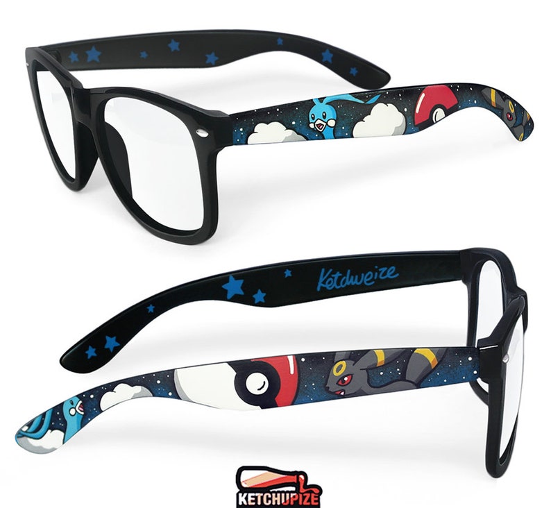 Picture of black prescription glasses, hand-painted with a Pokémon design, including Umbreon and Altaria and red and white Pokeballs on a black starry sky background, in white, blue, grey, black and red colors.